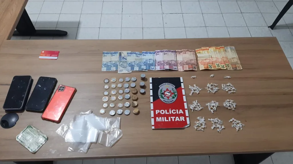 Maringá 98 FM —   Após denúncias anônimas, a Polícia Militar de Pombal desarticulou um ponto de tráfico de drogas no município no bairro Pereiros. Ao notar a aproximação da viatura, uma mulher identificada como Franciene Ferreira de Oliveira, a “Cilene”, tentou descartar um pacote com 20 pedras de substância análoga ao crack. Durante a revista na residência, os policiais encontraram mais entorpecentes, totalizando 93 pedrinhas de substância análoga ao crack apreendidas na ocorrência. A suspeita confessou o crime e afirmou que a droga pertencia ao seu companheiro, Juberlanio de Sousa Silva, que não foi localizado. Franciene foi presa em flagrante e levada à […]