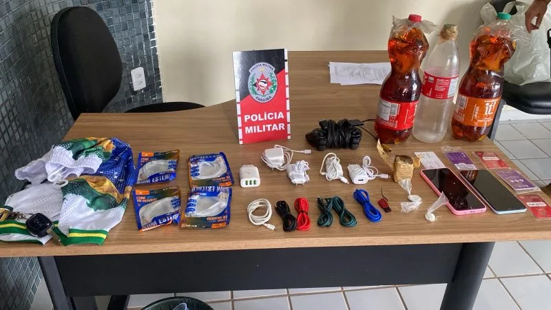 Maringá 98 FM — A Polícia Militar impediu a entrada de drogas, celulares e outros materiais proibidos na Colônia Penal Agrícola de Sousa, no Sertão da Paraíba. O caso foi registrado nesse domingo (14). De acordo com a PM, foram apreendidos maconha, cocaína, bebidas alcoólicas, pen drive, chips de telefonia, fones de ouvido, carregadores de celular, aparelhos celulares e até um controle de videogame. Todo o material seria arremessado por cima do muro da unidade prisional. Após a identificação da tentativa, os policiais realizaram buscas em uma área de mata próxima ao presídio e localizaram dois suspeitos envolvidos na ação. “Os dois suspeitos, um maior [&hellip;]