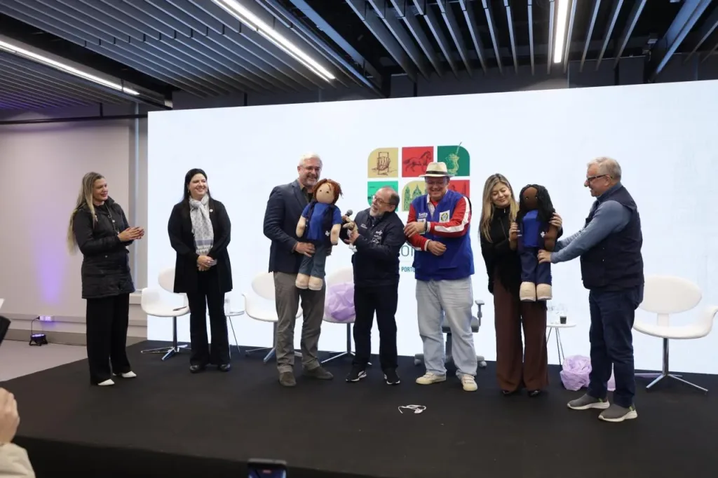 Maringá 98 FM — PORTO ALEGRE (RS) – Com direito a pronunciamentos marcantes e exibição de vídeo institucional, a diretora da Penitenciária de Reeducação Feminina Maria Júlia Maranhão, Tatiana Pimentel, participou ativamente do XXXIX Congresso do Conselho Nacional de Secretarias Municipais de Saúde (Conasems), realizado em Porto Alegre. Na oportunidade, foram apresentados oficialmente os mascotes de apoio institucional do evento: “SUSi” e “PegaSUS”, inteiramente confeccionados pelas reeducandas do projeto Castelo de Bonecas — uma política de ressocialização pioneira da Secretaria de Administração Penitenciária da Paraíba (Seap-PB) que já colhe frutos há mais de 13 anos na unidade prisional. Em sua fala, a diretora expressou a […]